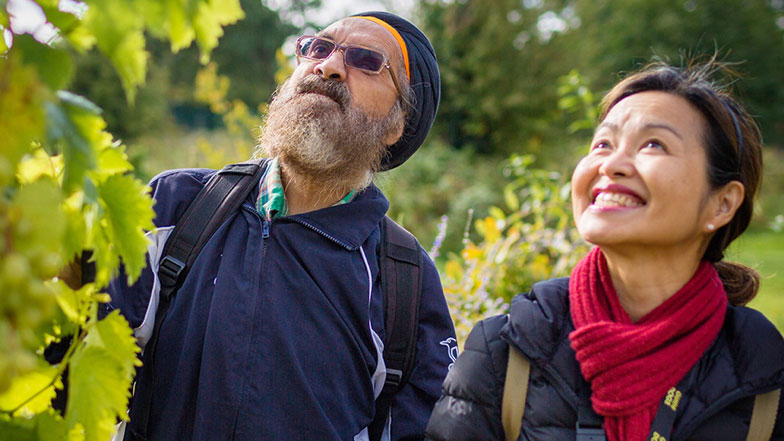 A My Guide volunteer helps a Sikh man to use a cane and navigate gardens A My Guide volunteer helps a Sikh man to use a cane and navigate gardens