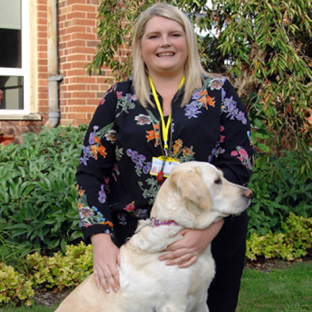 Lucy and Oliver sitting together in a garden in front of a red brick building