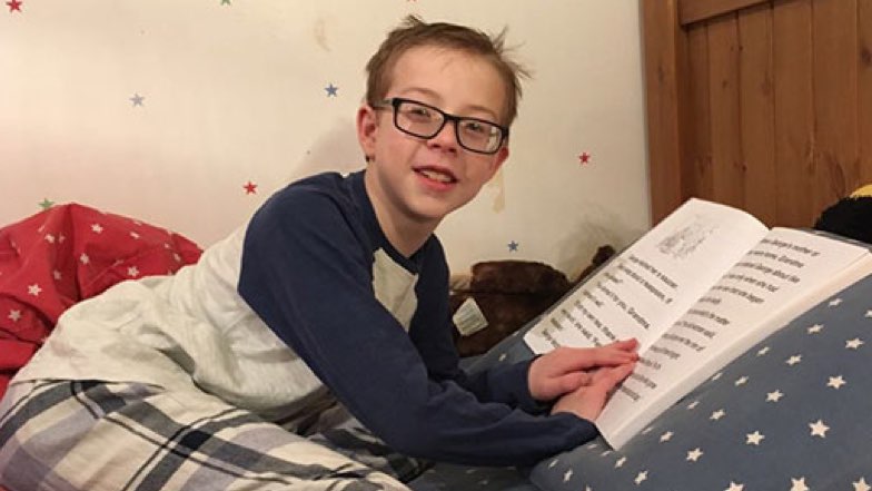 fin-on-his-bed-reading-a-guide-dogs-customeyes-book